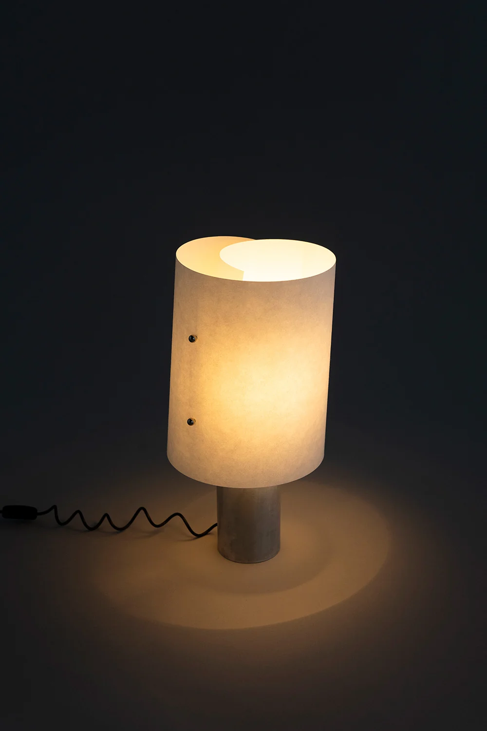 Curly lit, the washi shade glowing warm with light pooling on the floor
